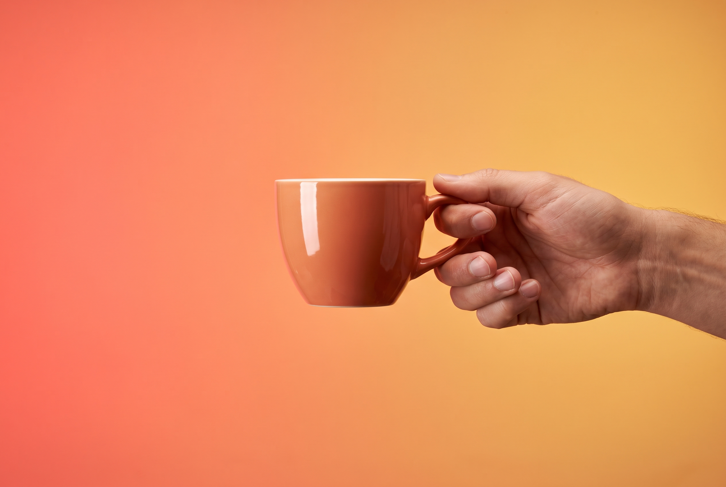Hand raising an iced coffee against a coral and gold gradient
