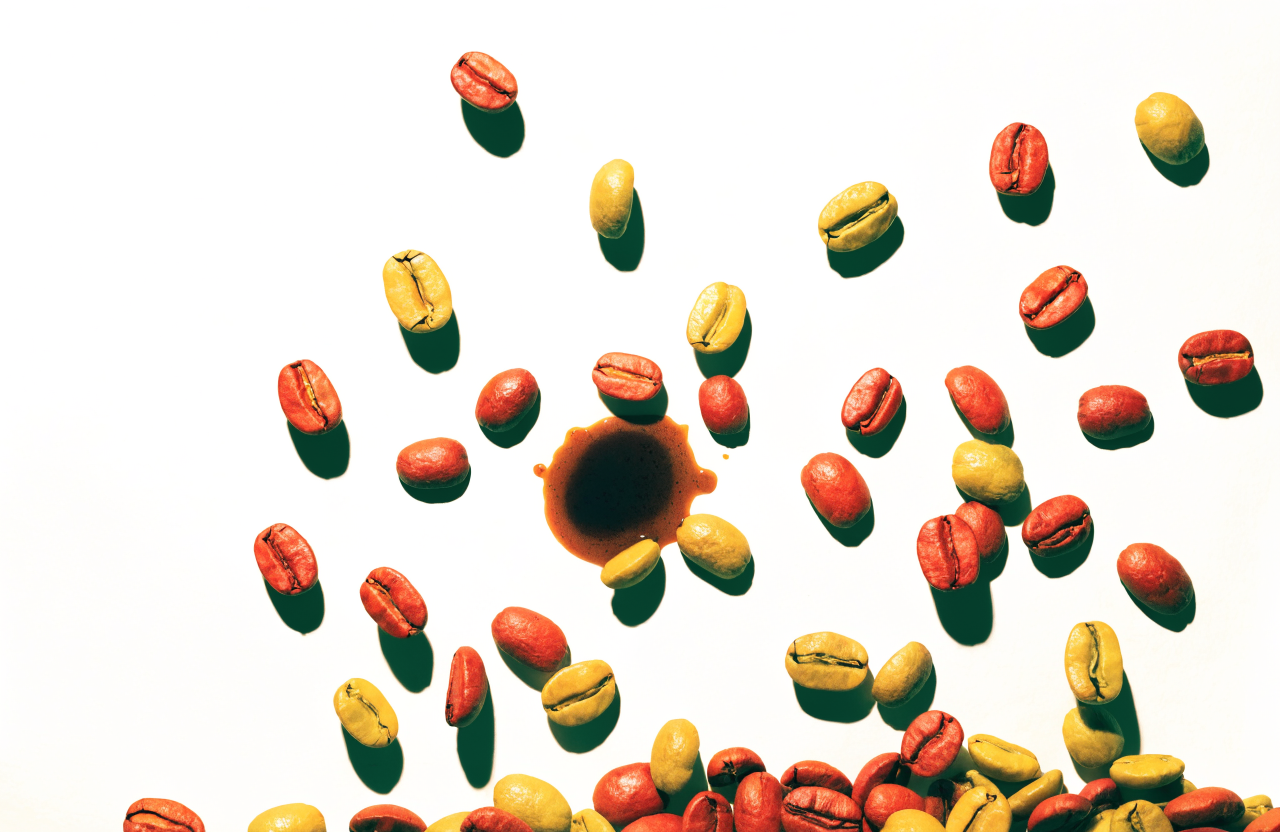 Scattered red and yellow coffee beans around an espresso splash