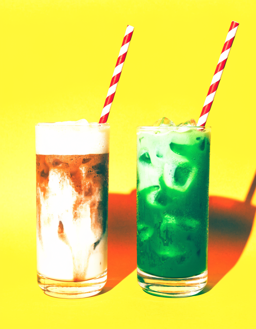 Iced coffee and iced matcha with striped straws on a yellow background